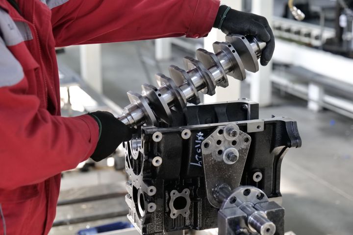 Crankshaft being seated into the engine block with main bearing shells visible